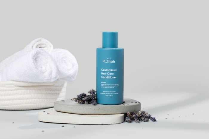 MDhair’s Microbiome Conditioner bottle with white towels